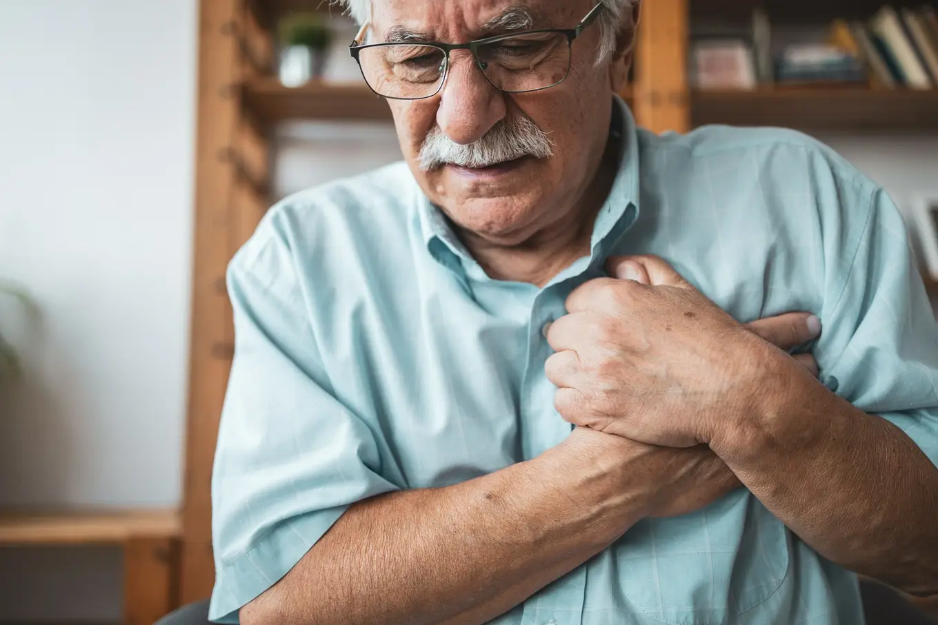 starszy mężczyzna w okularach z bólem w klatce piersiowej